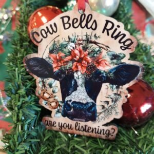 Handmade MDF wood Christmas ornament featuring a black and white cow with poinsettias, greenery, and the phrase Cow Bells Ring Are You Listening