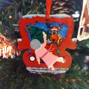 Funny Christmas ornament of a startled reindeer in a Santa hat driving a red truck while grandma flies through the air in a pink robe